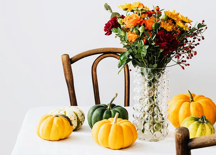 Fall Flowers in vase and autumn pumpkins on table